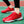 Rode sportschoenen met witte driehoekige patronen, gedragen op een groen sportveld. Comfortabele hardloopschoenen voor heren, ideaal voor atletiek.