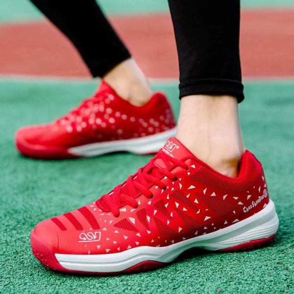 Rode sportschoenen met witte driehoekige patronen, gedragen op een groen sportveld. Comfortabele hardloopschoenen voor heren, ideaal voor atletiek.