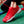 Rode sportschoen met witte driehoekige patronen, veters strikken, op groene ondergrond. Ideaal voor tennis, hardlopen, fitness. Comfortabel en stijlvol ontwerp.