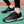 Zwarte sportschoenen met witte driehoekige patronen, gedragen op een groen sportveld. Ideaal voor hardlopen en fitness. Comfortabele en stijlvolle sneakers.