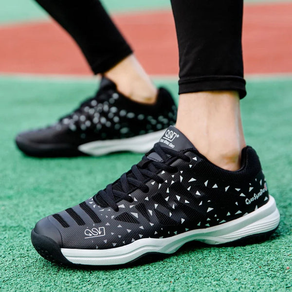 Zwarte sportschoenen met witte driehoekige patronen, gedragen op een groen sportveld. Ideaal voor hardlopen en fitness. Comfortabele en stijlvolle sneakers.