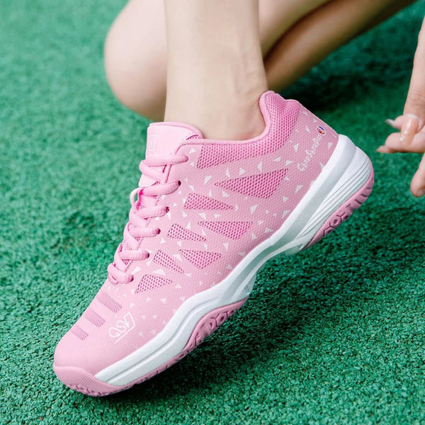 Roze tennisschoen met witte accenten op groene ondergrond, sportief ontwerp, ademend materiaal, ideaal voor dames, comfortabele pasvorm.