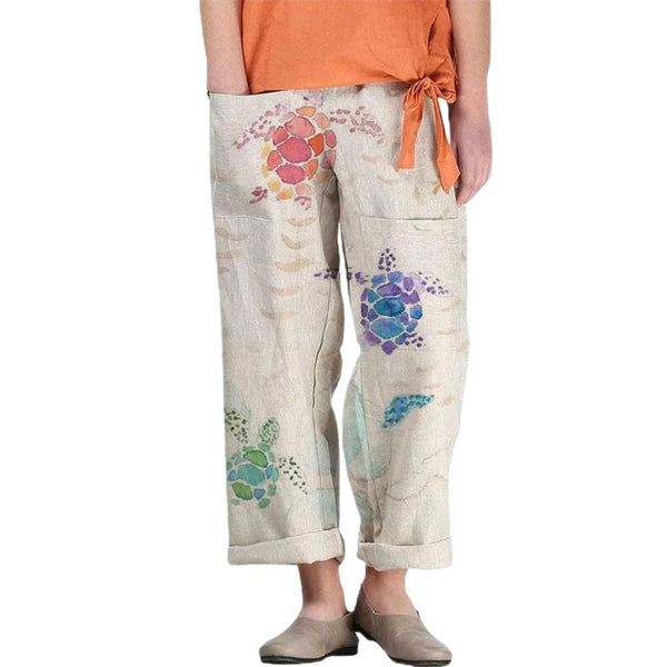 Vrouw draagt beige linnen broek met kleurrijke schildpadprint, oranje top. Modieuze dameskleding, casual stijl, lente/zomer outfit.