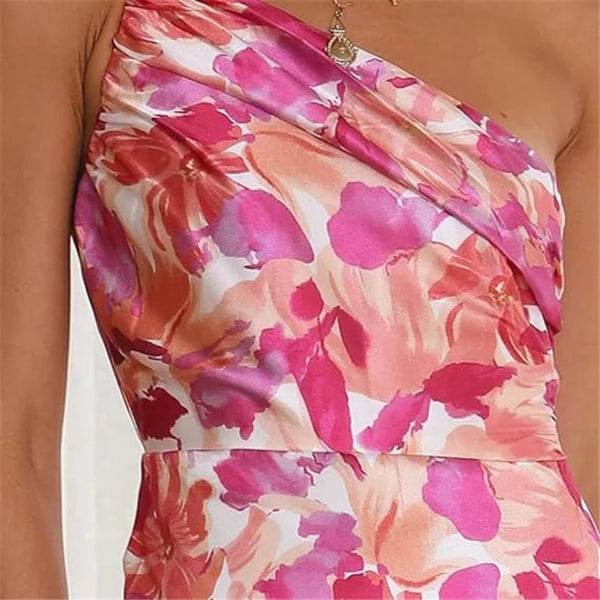Vrouw in roze en oranje bloemenjurk met asymmetrische halslijn, elegante zomerjurk, modetrend 2024, stijlvolle dameskleding.