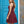 Vrouw in bordeauxrode kanten jurk voor blauwe deur, elegante avondjurk, modieuze kleding, stijlvolle outfit, trendy damesmode.