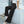 Vrouw in zwarte wijde broek en witte crop top leunt tegen witte muur. Mode, dameskleding, stijlvolle outfit, casual chic look.
