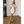 Vrouw in roze off-shoulder jurk met ruches, staand op houten vloer. Elegante mode, trendy avondkleding, stijlvolle outfit voor speciale gelegenheden.