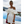 Vrouw in elegante witte off-shoulder jurk met ruches, bij infinity pool met zeezicht. Perfect voor zomerfeest of bruiloft. Luxe mode, strandlocatie.