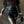 Vrouw in zwarte leren outfit met bontjas, korte broek en panty, draagt een stijlvolle handtas. Modieuze herfst- of winterkleding.