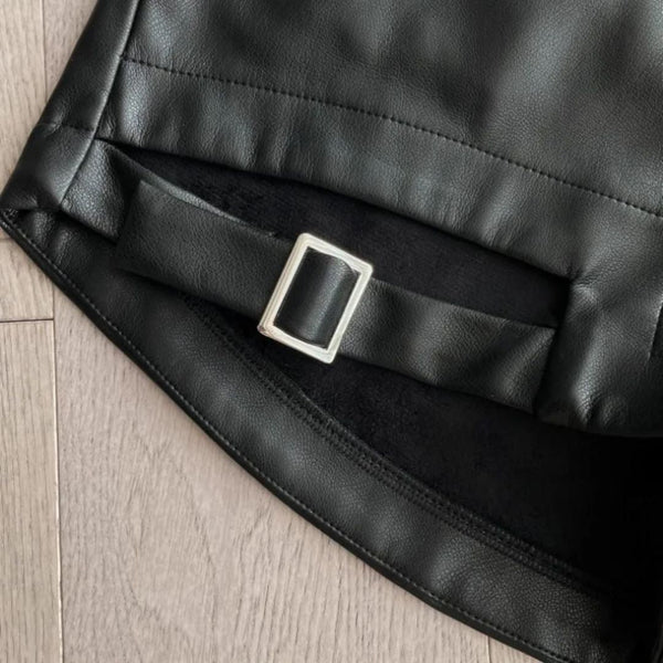 Zwarte leren rok met riemdetail en zilverkleurige gesp op houten vloer. Modieuze dameskleding, elegant design, hoogwaardige materialen.