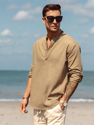 Stijlvolle man in beige linnen overhemd en zonnebril op strand, zomermode, casual herenkleding, strandoutfit, modeaccessoires.