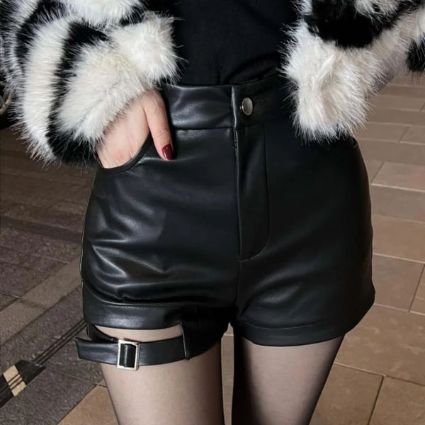 Vrouw draagt zwarte leren shorts met riemdetail, gecombineerd met zwart-witte bontjas. Modieuze winteroutfit, trendy dameskleding.
