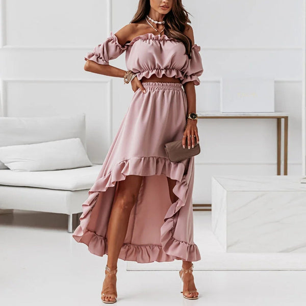 Vrouw in roze off-shoulder jurk met ruches, asymmetrische zoom en sandalen. Elegante zomermode, perfect voor feestelijke gelegenheden.