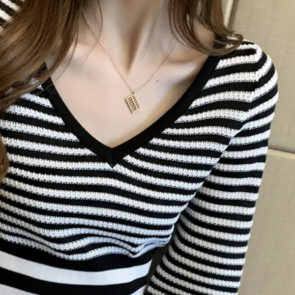 Zwart-wit gestreepte trui met V-hals en lange mouwen, gedragen door een vrouw. Modieuze dameskleding, casual stijl, trendy outfit.