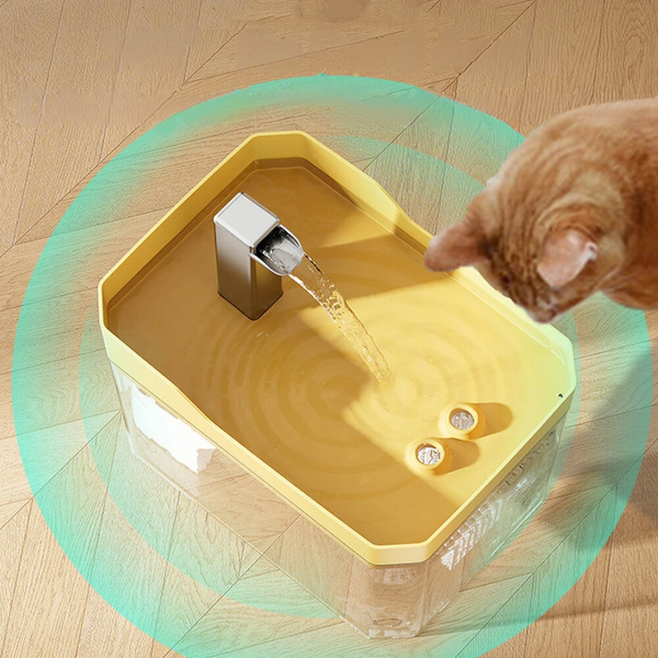 Gele kattenwaterfontein met stromend water op houten vloer, kat drinkt. Automatische drinkfontein voor huisdieren, modern design.