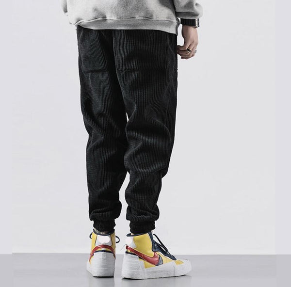 Zwarte corduroy broek, casual stijl, gedragen met kleurrijke sneakers. Comfortabele en modieuze keuze voor dagelijks gebruik.