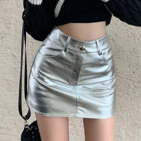 Zilveren metallic minirok, hoge taille, met knoopsluiting en zakken, gedragen door model. Trendy damesmode, glanzende rok, streetwear stijl.
