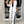 Vrouw in witte blazer en broek met zwarte strepen, zwarte top en hakken, poseert voor kledingkast. Stijlvolle zakelijke outfit, mode 2024.