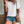 Witte geperforeerde dames T-shirt met korte mouwen, gecombineerd met denim shorts en bruine schoudertas, casual zomeroutfit voor dames.