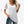 Vrouw draagt witte V-hals T-shirt met doorschijnende stippenmouwen, gecombineerd met gescheurde jeans. Modieuze casual dameskleding.