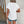 Vrouw in witte kanten blouse en denim shorts voor rustieke houten deur. Zomermode, casual outfit, dameskleding, boho-stijl.