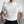 Man in witte gebreide trui met korte mouwen, staand in moderne woonkamer. Stijlvolle herenkleding, casual mode, minimalistisch interieur.
