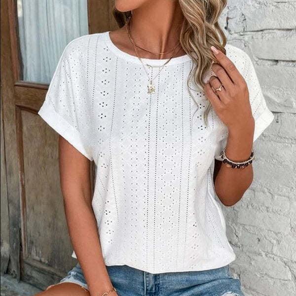 Vrouw draagt witte geperforeerde blouse met korte mouwen, gecombineerd met denim shorts. Zomerse mode, casual stijl, dameskleding.
