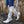Witte leren cowboylaarzen met studs, gedragen door persoon in blauwe jeans, tegen stenen muur. Trendy dameslaarzen, westerse stijl.