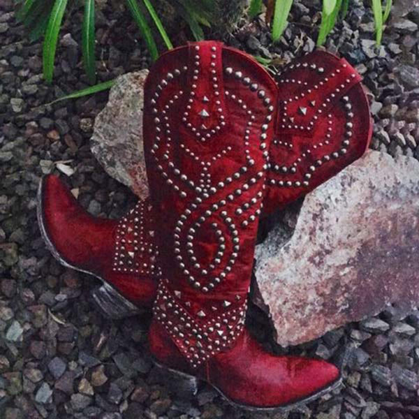 Rode cowboylaarzen met zilveren studs op grind en stenen achtergrond, westerse stijl, leren laarzen, opvallend design, outdoor modeaccessoire.