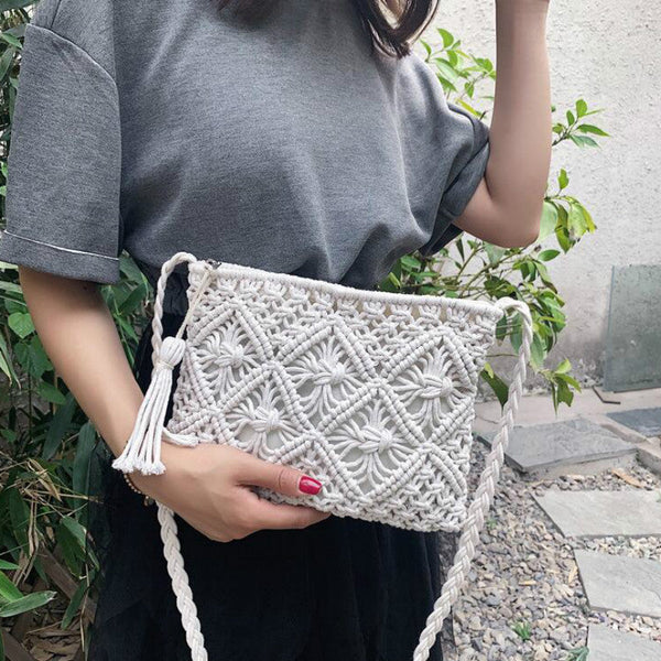 Vrouw met grijze top houdt een handgemaakte witte macramé schoudertas vast, perfect voor zomerse outfits. Bohemian stijl, trendy accessoire.