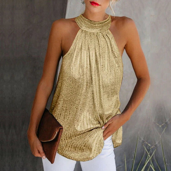 Vrouw in goudkleurige haltertop met plooien, witte broek en bruine clutch. Stijlvolle zomermode, elegante outfit voor avondje uit.