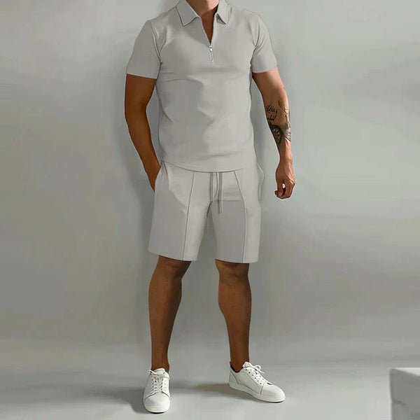 Grijze heren trainingspak set, bestaande uit een zomer poloshirt met korte mouwen en sport shorts. Perfect voor casual en sportieve gelegenheden.