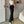 Vrouw draagt zwarte cut-out broek met wijde pijpen, gecombineerd met een witte crop top. Trendy mode, casual outfit, moderne stijl.