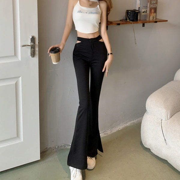 Vrouw draagt zwarte cut-out broek met wijde pijpen, gecombineerd met een witte crop top. Trendy mode, casual outfit, moderne stijl.