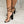 Zwarte hoge hakken met transparante bandjes en veterdetails, gedragen door een vrouw op een marmeren vloer. Stijlvolle damesmode, elegante schoenen.