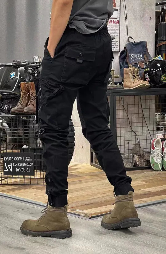 Man in zwarte cargobroek en bruine laarzen in een winkel met motoraccessoires. Casual kleding, stedelijke mode, herenkleding, motorwinkel.