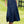 Vrouw in witte blouse en lange denim rok met riem, staand op grasveld. Stijlvolle herfstmode, casual outfit, dameskleding, bruine laarzen.