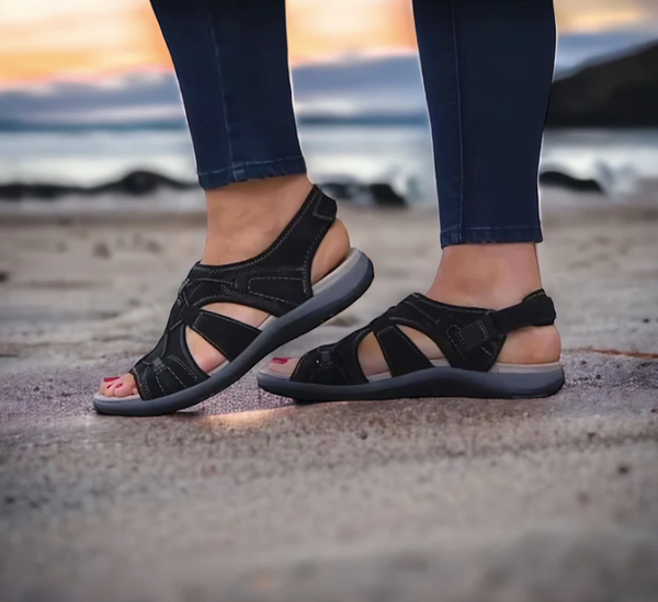 Zwarte sandalen voor dames op een strand bij zonsondergang, comfortabele wandelschoenen, ideaal voor zomerse avonturen en casual outfits.