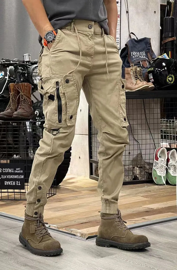 Beige cargobroek met meerdere zakken en zwarte ritsen, gedragen met bruine leren laarzen. Ideaal voor outdoor activiteiten en casual mode.