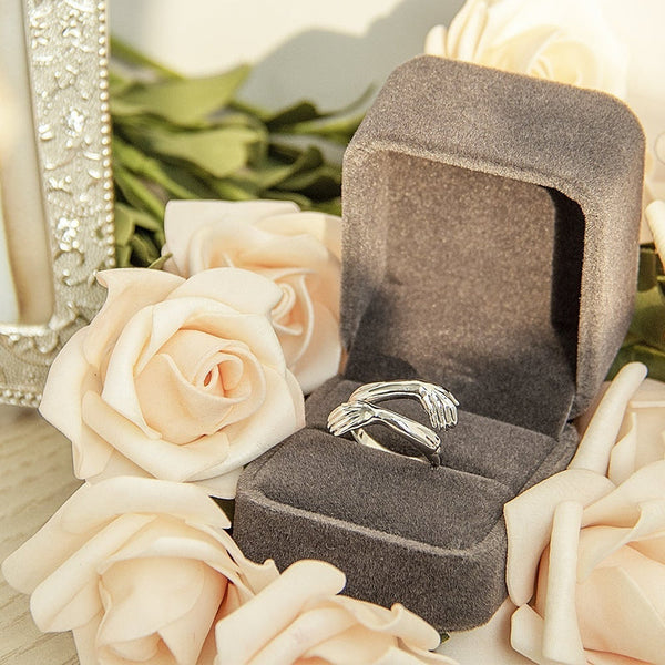 Zilveren ring in luxe grijze sieradendoos, omringd door crèmekleurige rozen. Perfect cadeau voor verloving of bruiloft. Elegante sieradenpresentatie.