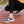 Grijze ademende sportschoenen met witte zolen, gedragen door een persoon in zwarte broek op een rode atletiekbaan. Comfortabele slip-on sneakers.