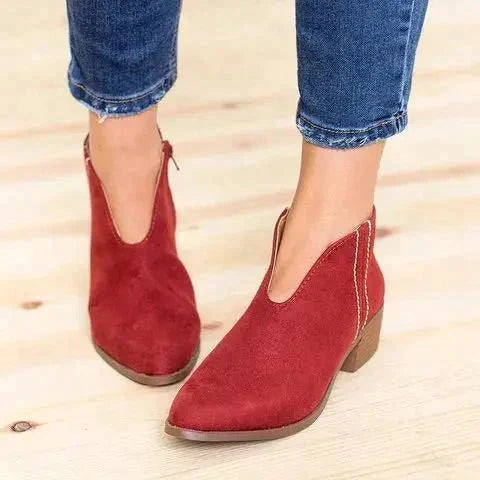 Rode suède V-cut enkellaarsjes met blokhak, gedragen met blauwe jeans. Trendy dameslaarzen, comfortabele pasvorm, modieuze herfst- en winterstijl.