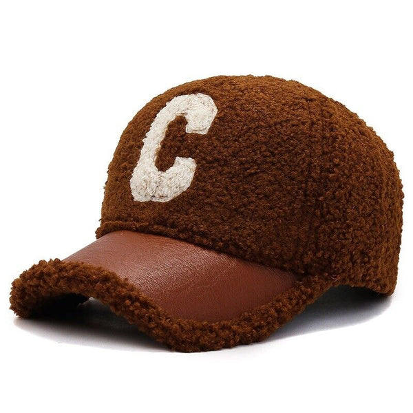 Bruine baseballpet met geborduurde witte letter "C", gemaakt van pluche materiaal en leren klep. Stijlvolle unisex accessoire voor casual outfits.