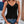 Vrouw in zwarte kanten top en denim shorts, zomerse outfit, casual mode, trendy kleding, buitenomgeving met bloemen en blauwe deur.