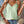 Vrouw in mintgroene kanten top en denim shorts, draagt een witte schoudertas en sieraden. Zomermode, casual outfit, trendy kledingstijl.