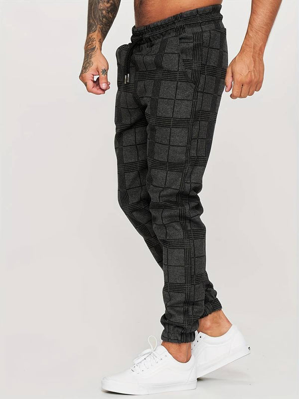 Grijze geruite joggingbroek voor heren, casual streetwear, comfortabele pasvorm, gecombineerd met witte sneakers. Perfect voor dagelijks gebruik.