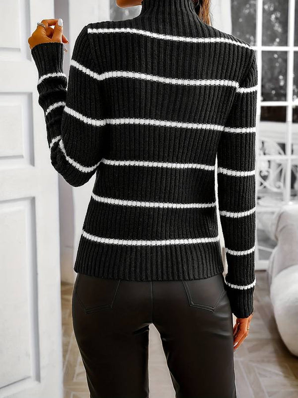 Vrouw in zwart-wit gestreepte coltrui en zwarte leren broek, staand in moderne woonkamer. Stijlvolle wintermode, casual chique outfit.