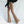 Vrouw in luipaardprint flared broek en zwarte blouse, modetrend, stijlvolle dameskleding, retro look, comfortabele pasvorm, casual outfit.