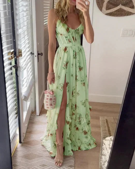 Vrouw in lange, lichtgroene bloemenjurk met hoge split, poseert voor spiegel. Zomerse mode, elegante avondjurk, trendy dameskleding.