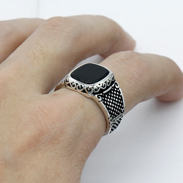 Zilveren herenring met zwarte onyx steen en gedetailleerd filigraan ontwerp, gedragen aan een hand. Stijlvolle sieraden voor mannen, elegant accessoire.